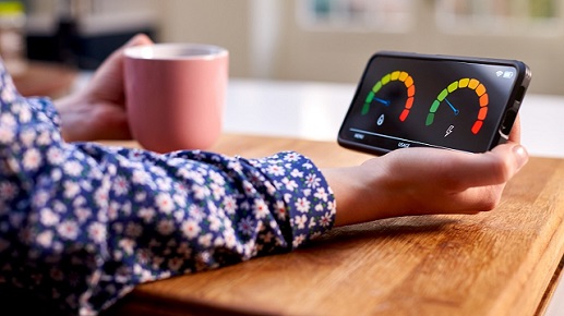 A person holding a mug and a smart meter in home display