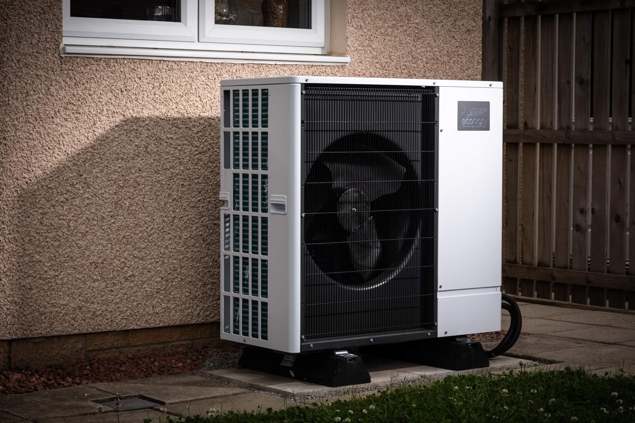 air source heat pump with a dark brown fence to the right