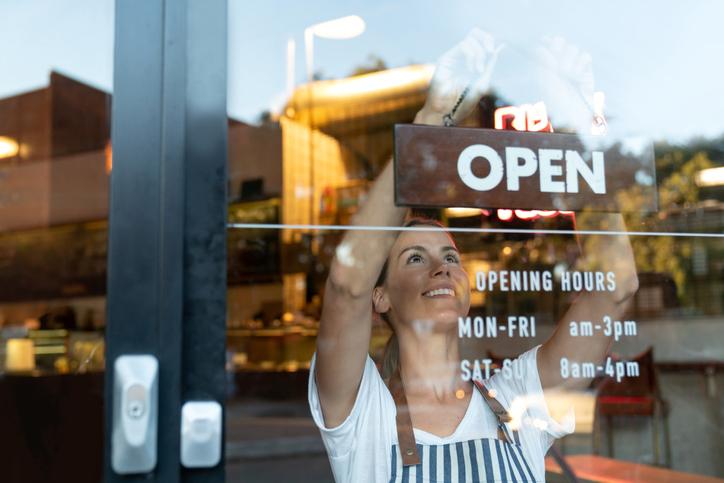 Cafe worker smiling with an open sign