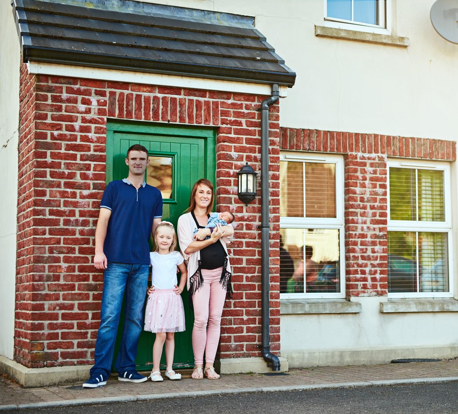 Young family standing outside their home